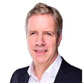 Eine Person in einem dunklen Anzug und weißem Hemd.