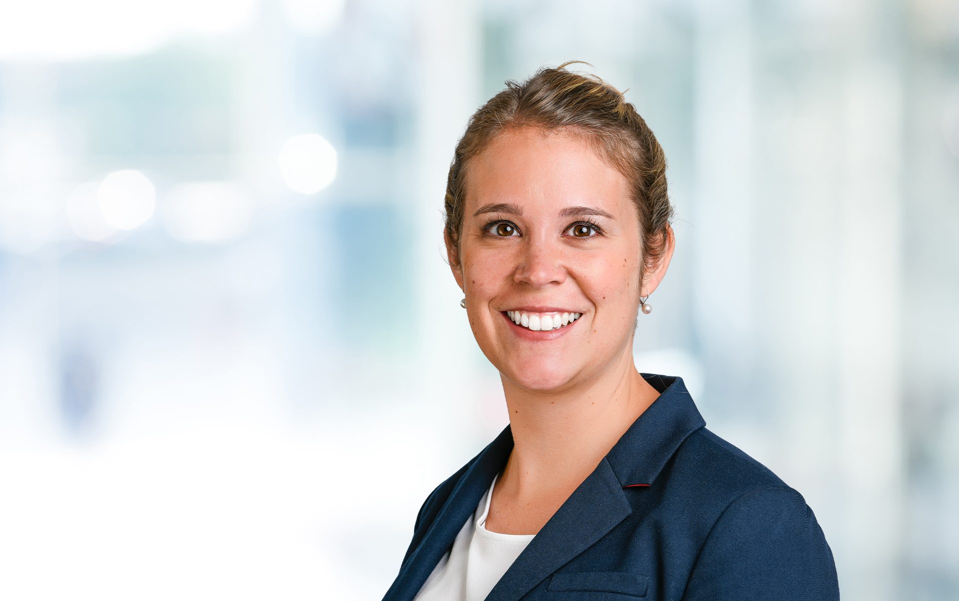 Die Person trägt ein formelles dunkelblaues Jackett und ein weißes Hemd.