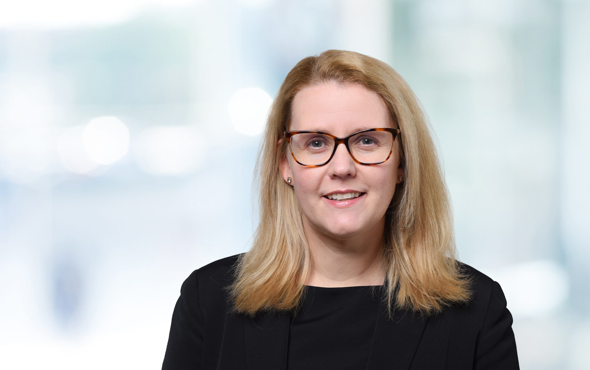 Die Person trägt ein formelles schwarzes Kleidungsstück mit einem hellen Hintergrund. Das Bild schafft eine professionelle Atmosphäre im Rahmen eines möglichen Geschäftsfotos.