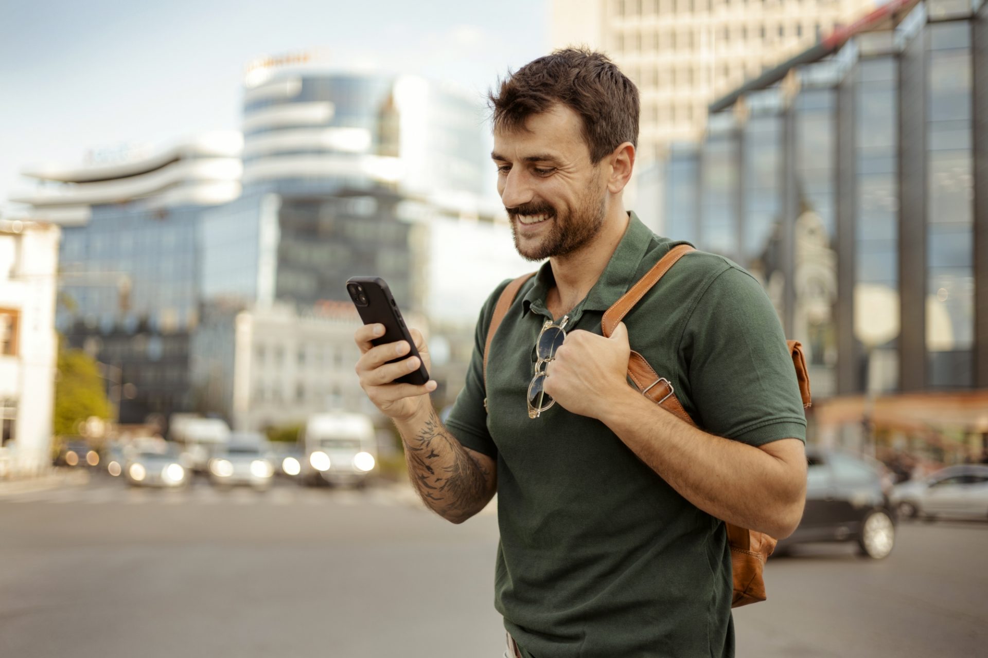 Urban-mobility Zahlungen Ein Mann mit Smartphone auf einer belebten Straße, im Hintergrund moderne Gebäude und Autos.